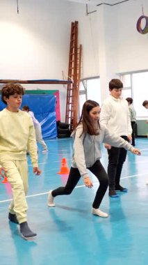 Öğrenciler, beden eğitimi dersinde eğitmenle birlikte hareket ediyor, denge ve koordinasyon uyguluyor.