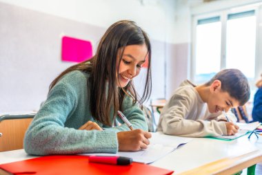 Mutlu ilkokul çocukları ders sırasında notlara hevesle yazıyorlar, derslerle uğraşıyorlar ve okul deneyimlerinin tadını çıkarıyorlar.