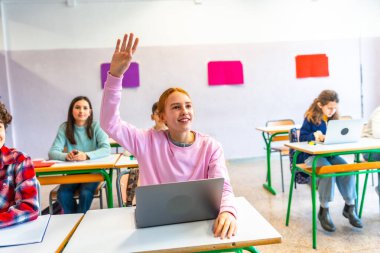 Akıllı öğrenci, ders sırasında bir soru sormak için elini kaldırıyor. Modern eğitime katılım ve bağlılık gösteriyor.