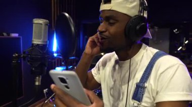 Profesyonel müzik stüdyosu ayarları. Yetenekli sanatçı vokalleri kaydediyor. Kulaklık takarken ve daha yoğun mikrofon kullanırken melodik şarkıları mükemmelleştiriyor.