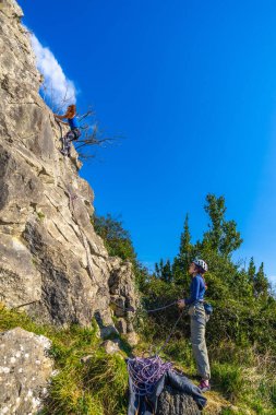 Güneşli bir günde zorlu bir tırmanışa katılan iki kadın dağcı, takım çalışması, yetenek ve doğanın engellerini aşmada kararlılık gösteriyorlar.