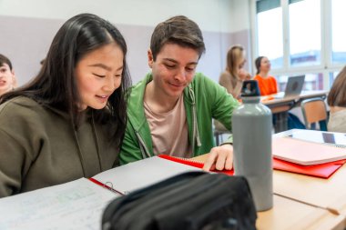 İki lise öğrencisi, bir sınıfta takım çalışması ve eğitim alanında işbirliği sergileyen bir proje üzerinde birlikte çalışıyorlar.