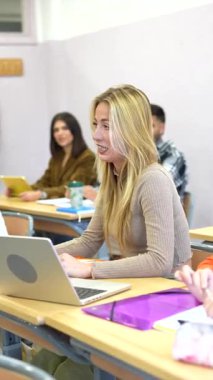 İlgili bir sınıf tartışmasına aktif olarak katılan odaklanmış üniversite öğrencisi, not almak ve araştırma yapmak için bir dizüstü bilgisayar kullanıyor
