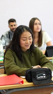 Asyalı bir öğrenci aktif olarak bir üniversite konferansına katılıyor, akademik tartışmaya katkı sağlıyor