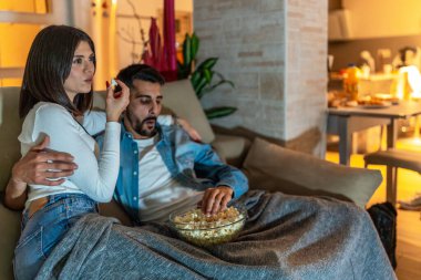 Romantik çift kanepede dinleniyor, televizyon seyrediyor ve sıcak oturma odalarında bir kase patlamış mısır paylaşıyor.