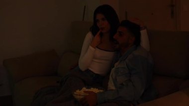 Genç çiftleri rahatlatıyor. Özel film gecelerini paylaşıyorlar. Oturma odasındaki kanepede sarılıyorlar.