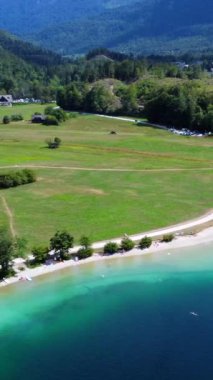 Turistler, yemyeşil yemyeşil bir göl kenarında yazın tadını çıkarıyorlar ve ılık güneşin tadını çıkarıyorlar.