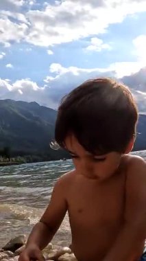 Sakin, berrak su, güneşli bir yaz gününde, dağlarla çevrili, Bohinj Gölü 'nde kumlu bir kumsal turu atar.