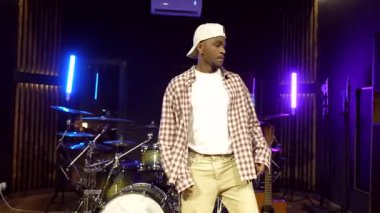 Yaratıcı enerjisiyle dans eden genç siyahi erkek, profesyonel kayıt stüdyosundaki dinamik hip hop hareketi ile tutkusunu ifade ediyor.