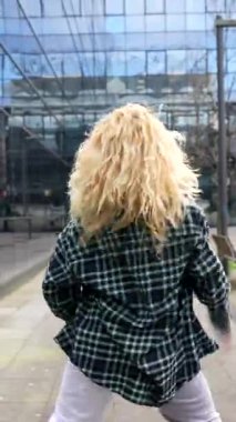 Canlı genç dansçı dinamik şehir koreografisi yapıyor, tutkulu enerji ve şık hareketlerle modern şehir manzarasına karşı serbest stil hareketleri sergiliyor.