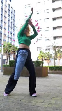 Şehir ortamında hareketli hareketler sergileyen enerjik dansçı dinamik koreografi yoluyla neşe ve özgürlüğü ifade ediyor.