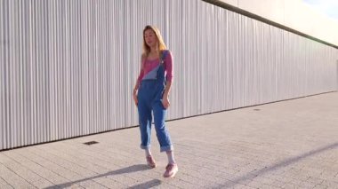 Enerjik sarışın dansçı şehir dansı yeteneklerini modern mimari arkaplana karşı dinamik bir performansla sergiliyor