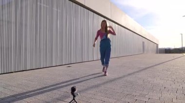 Açık havada dans etmeden önce kamerasını ayarlayan genç sarışın dansçı.