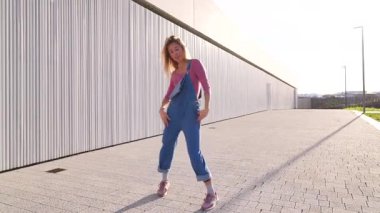 Enerjik sarışın dansçı şehir dansını sergiliyor, dinamik koreografi yoluyla kendini ifade ediyor.