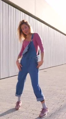 Sarışın kadın dansçı modern mimari arka plana karşı çağdaş sokak tarzında dinamik kent dansı hareketleri sergiliyor.