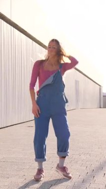 Genç sarışın kadın dinamik şehir dansı yapıyor açık havada, enerjik sokak dansı stili ve bireysel serbest dans koreografisi yoluyla tutkuyu ifade ediyor.