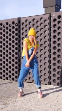 Sarışın dansçı modern mimari arkaplana karşı dinamik sokak dansı yaparak tutkulu hareketlerle yaratıcı enerjiyi ifade ediyor.