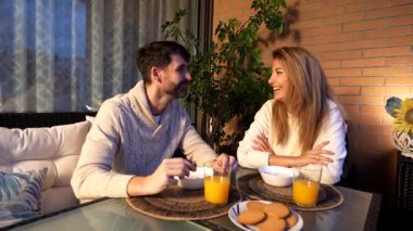 Romantik çift evlerinin balkonunda güzel bir yoğurt, meyve suyu ve kurabiye kahvaltısı yapıyorlar.