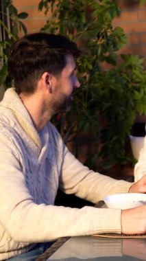 Sevgi dolu çift sabah yemeğinin tadını çıkarıyor, güneşli terasta kahvaltıyı paylaşıyor rahat bir bağ ve neşeli bir etkileşimle.