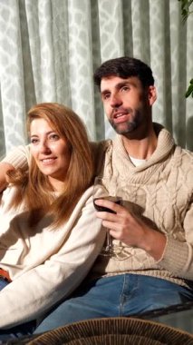 Romantik çift rahat bir kanepede şarap içip sohbet ederek sıcak ve samimi bir ortam yaratıyor.