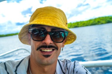 Siargao, Filipinler 'deki geleneksel bir banca teknesinde güneş gözlüğü takan ve şapka takan genç adam gülümsedi.