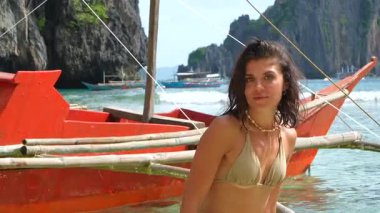 Tatilin tadını çıkaran genç bir kadın geleneksel bir bangka teknesinde poz veriyor. El Nido, Palawan, Filipinler 'in güzel sularında.