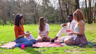 Arkadaşlar dışarıda toplanıyor, yeşil çimlerde oturuyor, parlak güneş ışığı altında iskambil oynuyor, kahkahalarınızı paylaşıyor ve hafta sonu eğlencesine sıcak bir bağ kuruyorsunuz.