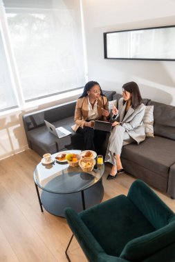 İki iş kadını bir iş gezisi sırasında otel odalarında kahvaltı edip iş tartışıyorlar.