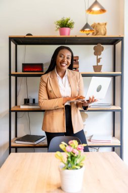 Mutlu yönetici, şık bir otel odasında dizüstü bilgisayarla çalışıyor. Üretken bir iş seyahatinin keyfini çıkarırken bağlantıda kalıyor.