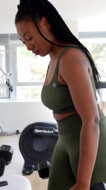 Kararlı kadın, otel konaklama sırasında vücut geliştirme rutinine odaklanarak, dambıllarıyla biseps kıvırıyor.