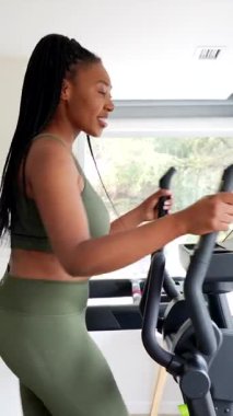 İş kadını seyahat ederken, otel spor salonunda eliptik makine kullanarak spor yapmaya devam ediyor.