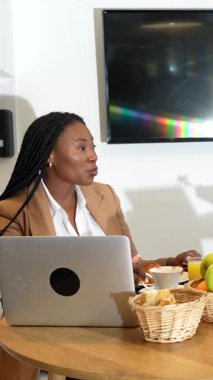 Profesyonel iş kadınları kahvaltılarını paylaşırken, iletişim kurarken ve iş stratejilerini tartışırken, otel konaklama sırasında teknolojiyi kullanırken, kurumsal işbirliği ve liderliği somutlaştırırken,