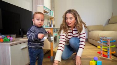 Mutlu anne ve çocuk, rahat bir oturma odasında oyun oynuyorlar etkileşimli oyun oynayarak bağlarını güçlendiriyorlar.