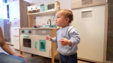 Sevgi dolu anneyle oynaşan, evde oyuncak mutfağını keşfeden, erken çocukluk öğrenme ve gelişimi sağlayan oyuncu çocuk.