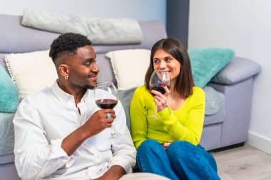 Çeşitli çiftler evde dinleniyor, rahat bir koltukta şarap içip sohbet ediyorlar, sıcak ve davetkar bir ortam yaratıyorlar.