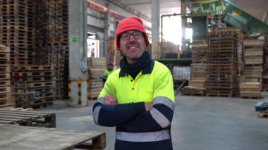Denetmen, bir geri dönüşüm fabrikasında katlanmış kollarla gülümsüyor, atık yönetimi konusunda güven ve uzmanlığı somutlaştırıyor