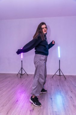 Dans ve sanatsal ifadeye olan tutkusunu gösteren renkli ışıklarla aydınlatılmış bir dans stüdyosunda koreografi uygulayan kadın dansçı.