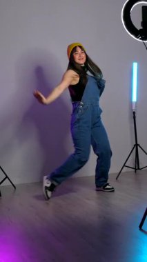 Neon ışıklı stüdyo içinde dinamik hareketlerle çağdaş koreografi uygulayan yetenekli kadın dansçı, kent dans stili ile sanatsal tutkularını ifade ediyor.