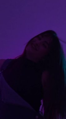 Enerjik dansçı canlı neon ışıklarının altında hareketler sergiliyor. Tutku ve ritmi ifade ediyor.