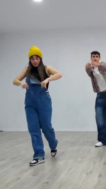 Genç dansçılar hip hop yeteneklerini parlak bir dans stüdyosunda sergileyerek dinamik hareketleri enerji ve hassasiyetle gerçekleştirirler.