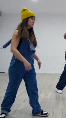 Parlak bir stüdyoda dinamik bir gösteri yapan genç dansçılar, senkronize hareketler ve enerjik ifadelerle hip hop becerilerini sergiliyorlar.