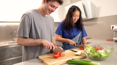 Çok ırklı ortaklar canlı, besleyici bir salata yaratırken şık mutfak alanlarında yakın işbirliği yapıp taze malzemeleri birlikte doğruyorlar.