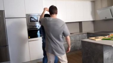 Çok ırklı bir çift, birlikte dans ederken mutlu anları paylaşır. Parlak, çağdaş mutfak ortamında sevgi ve bağlarını ifade ederler.