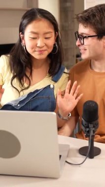 Podcast 'te işbirliği yapan genç çift, ev stüdyosunda dizüstü bilgisayar ve mikrofon kullanarak ses içeriğini birlikte kaydediyor.