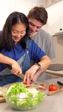 Genç çift modern mutfaklarında sağlıklı bir salata hazırlarken eğleniyor.