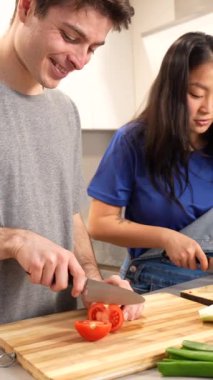 Çok ırklı bir çift taze salatayı birlikte hazırlıyor, şık bir mutfakta uyumlu bir şekilde çalışıyor aynı zamanda neşe ve takım çalışması ile canlı sebzeler doğruyor.
