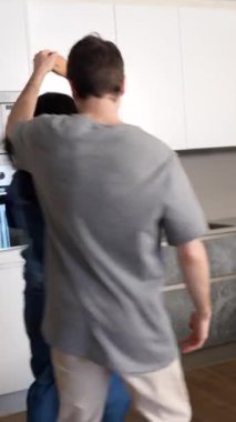 Genç çok ırklı çift, samimi dans anlarını paylaşıyor, modern, parlak mutfakta neşeyle birlikte hareket ediyor, ritmik, oyuncu hareketlerle sevgi ve bağlarını ifade ediyorlar.