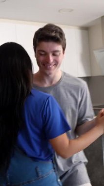 Çok ırklı çift, neşeli dans anlarını parlak, çağdaş mutfakta paylaşıyor. Kendiliğinden hareket ederek neşe ve yakınlık duygularını ifade ediyorlar.