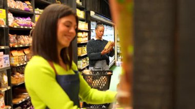 Organik ürün seçimi yoluyla müşteriye rehberlik eden yardımsever bir market çalışanı, modern perakende piyasasında kişisel alışveriş yardımı sunuyor