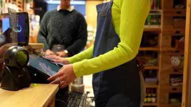 Profesyonel kasiyer organik ürünleri tarıyor sürdürülebilir sıfır atık bakkalında ahşap kasada, eko dostu perakende hizmeti gösteriyor